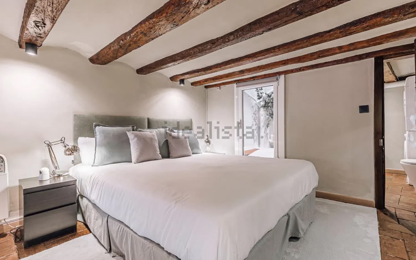 Dormitorio del altillo con cama doble bajo las vigas