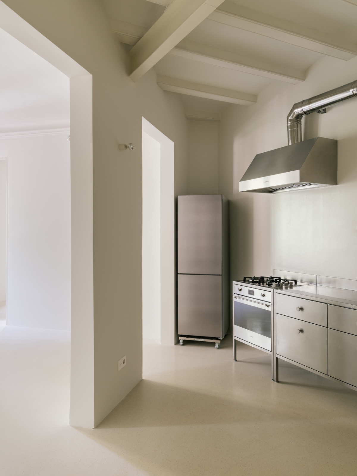 Cocina de acero inoxidable con campana industrial y las vigas de madera del techo