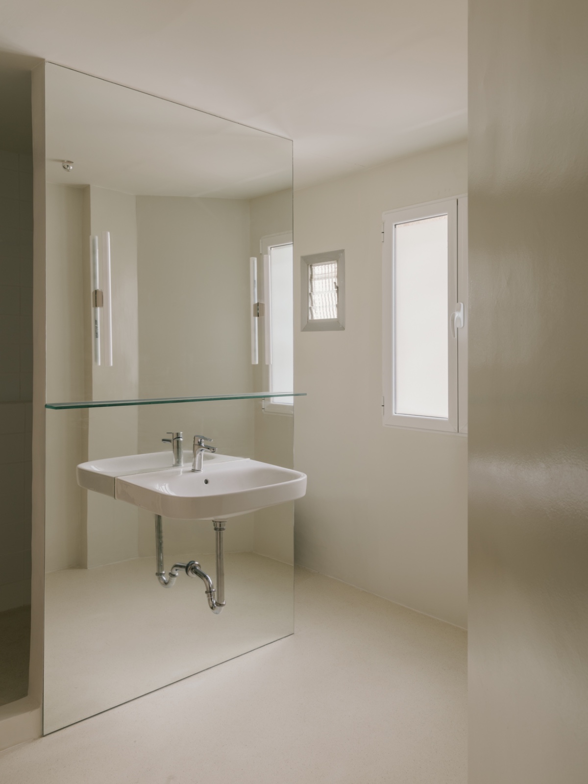 Baño exterior con lavabo suspendido y espejo de suelo a techo
