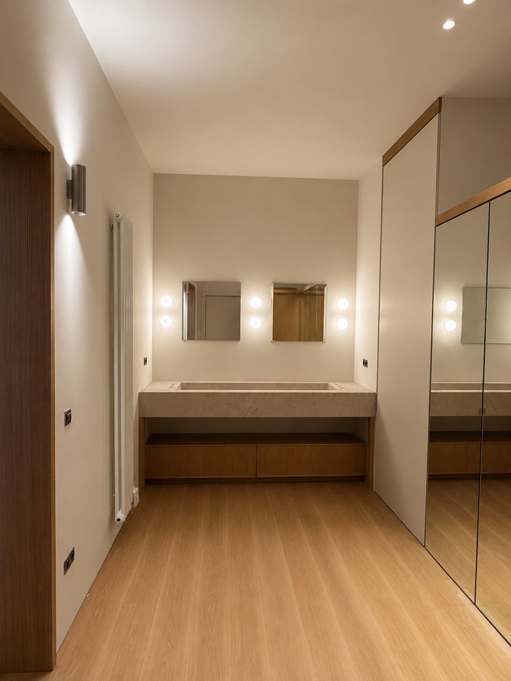 Vestidor con tocador de mármol, espejos iluminados y frentes de armario en espejo