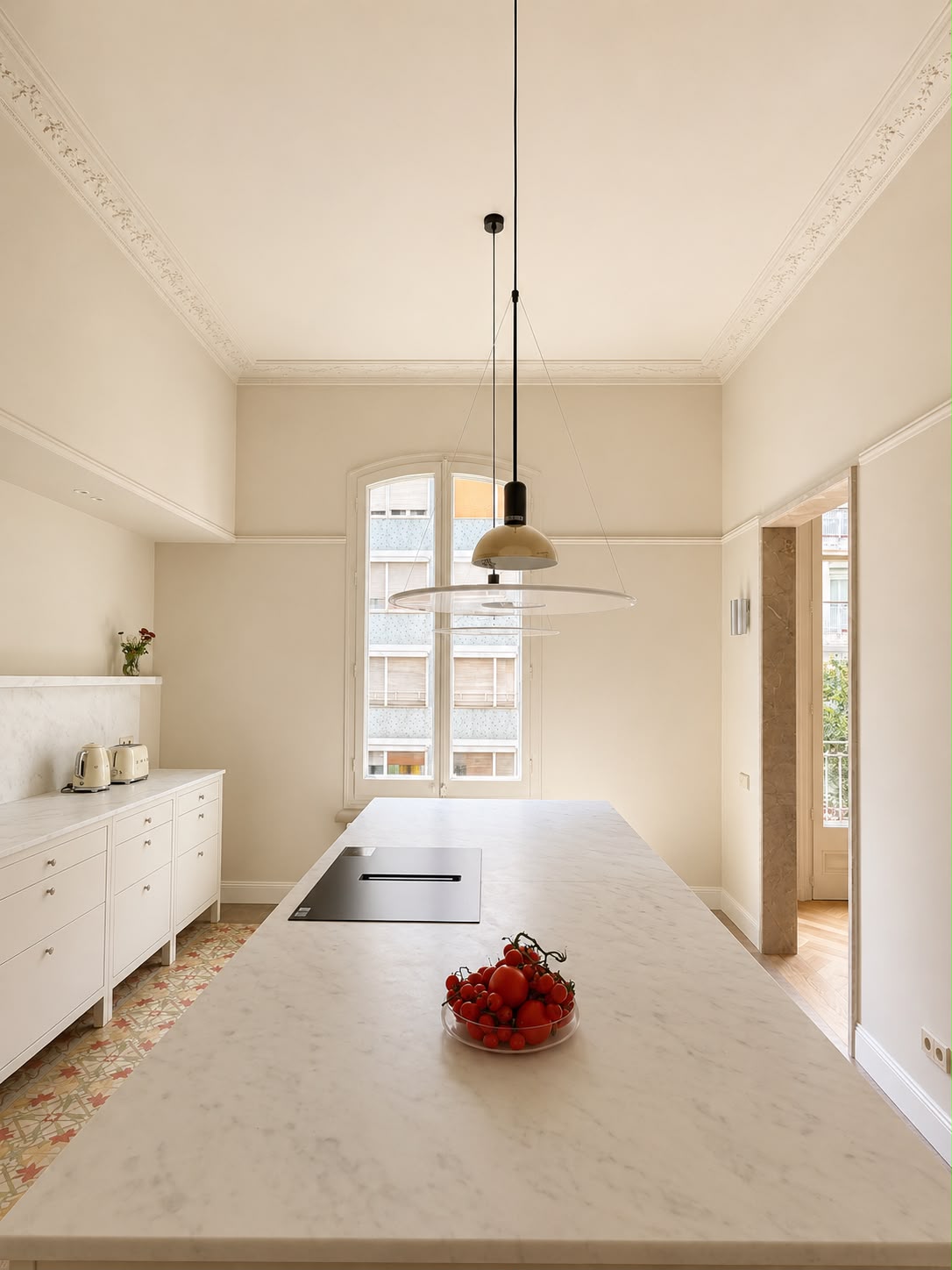 Cocina con la isla de mármol, la ventana en arco y el suelo de mosaico hidráulico