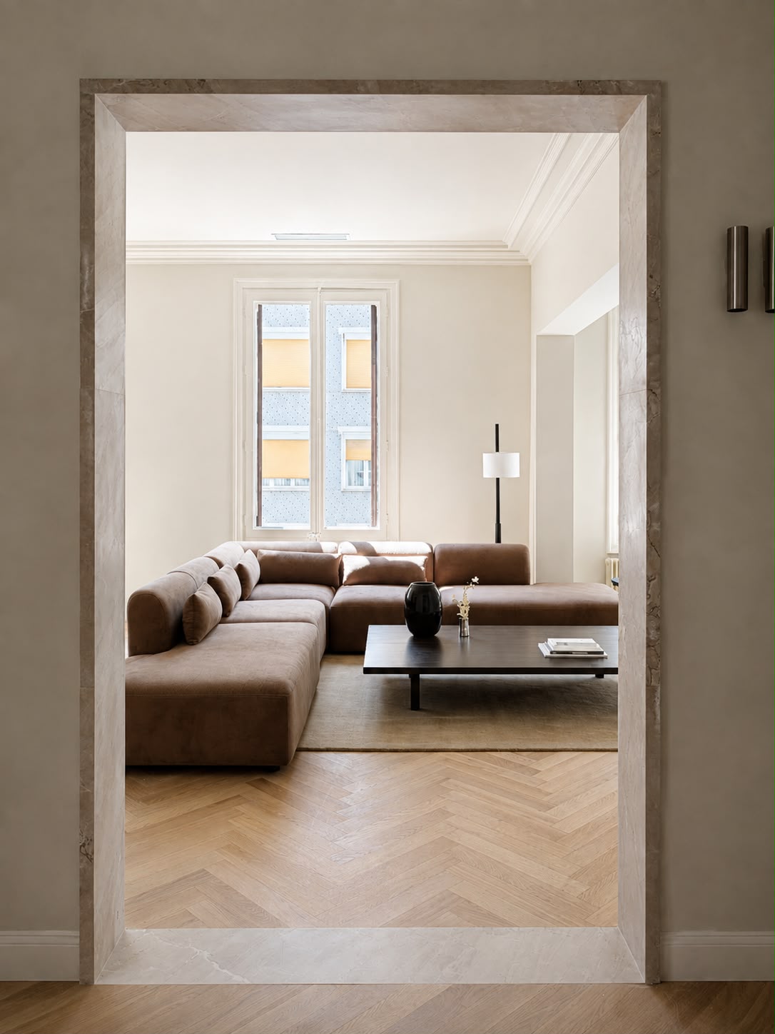 Salón con sofá modular, mesa baja oscura y la ventana alta al fondo